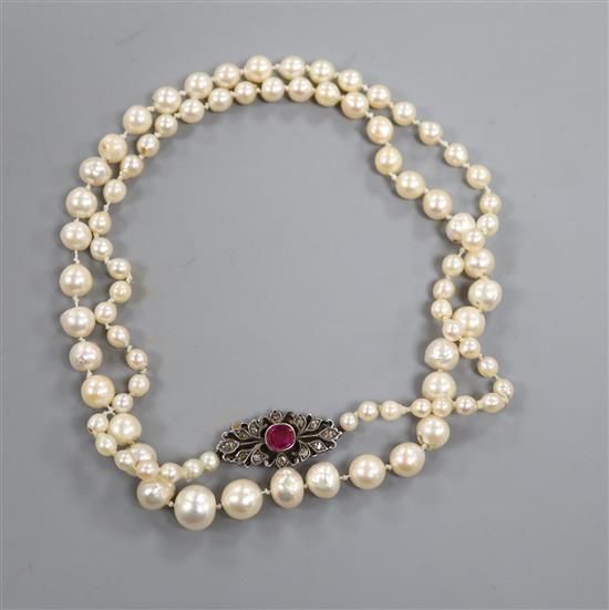 A single strand cultured pearl necklace with ruby and diamond set yellow metal clasp, 64cm.